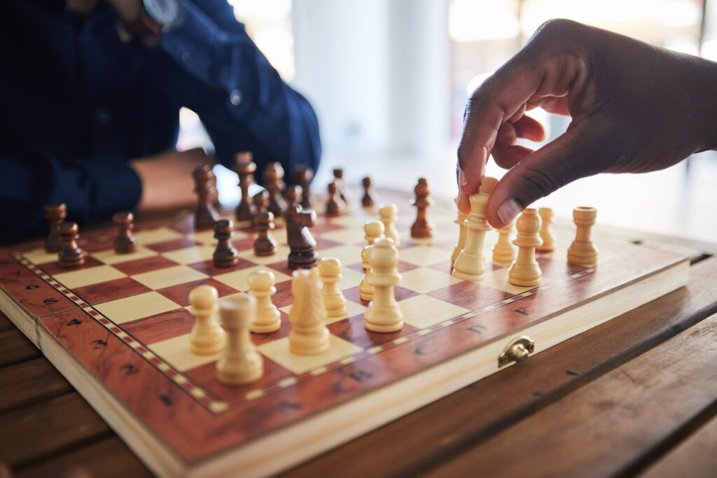 Two people playing chess on a wooden board