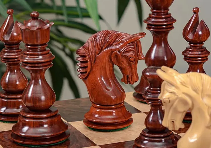 Close-up of intricately carved wooden chess pieces, including a knight, on a chessboard