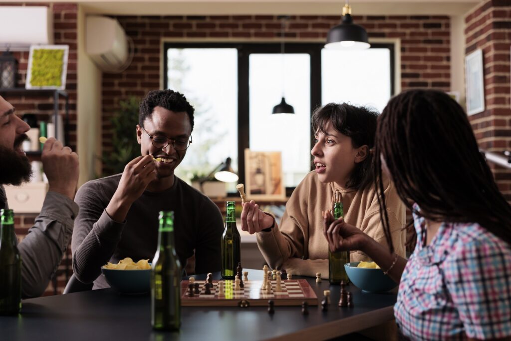 A group of friends playing chess and enjoying snacks at a cafe, engaging in a lively conversation.