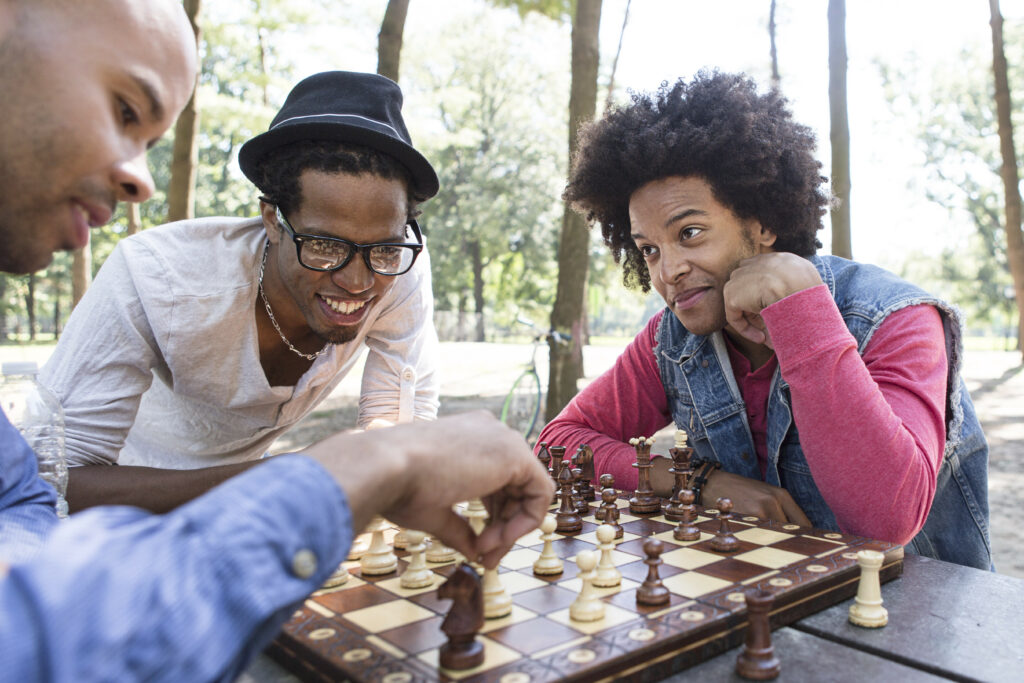 Three friends enjoying a game of chess outdoors.